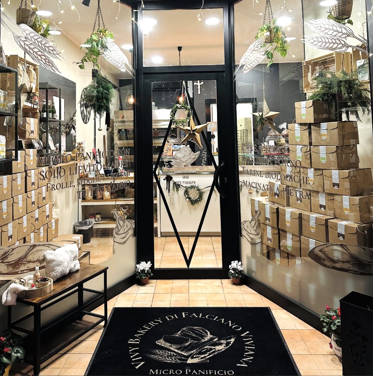 L’ingresso di Vivy Bakery: vetrina decorata con spighe, scatole kraft impilate e tappeto con il logo